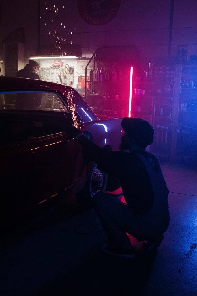 pexels-photo-4488666-4488666 A mechanic repairs a vehicle in a neon-lit garage, enhancing the modern automotive workspace ambiance.
